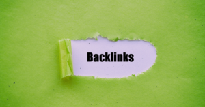 The word "Backlinks" written in black on a white background, revealed through a torn hole in a green piece of paper.