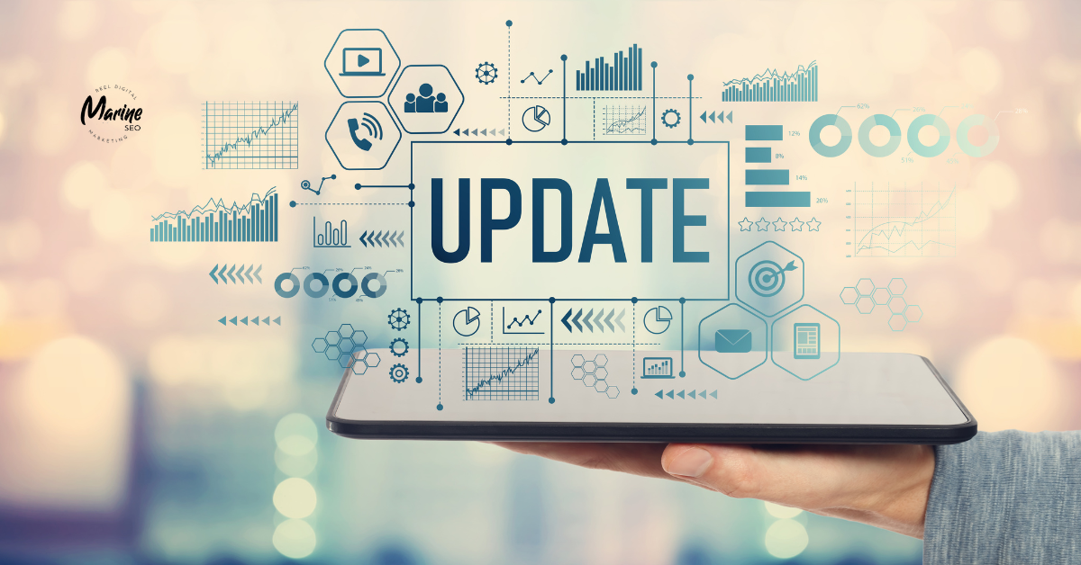 Close-up of a hand holding a tablet displaying the word “UPDATE” surrounded by digital icons, graphs, and charts, with the Marine SEO logo in the upper left corner.